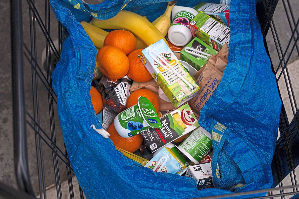 A person stocks their trolley with food from a community fridge.