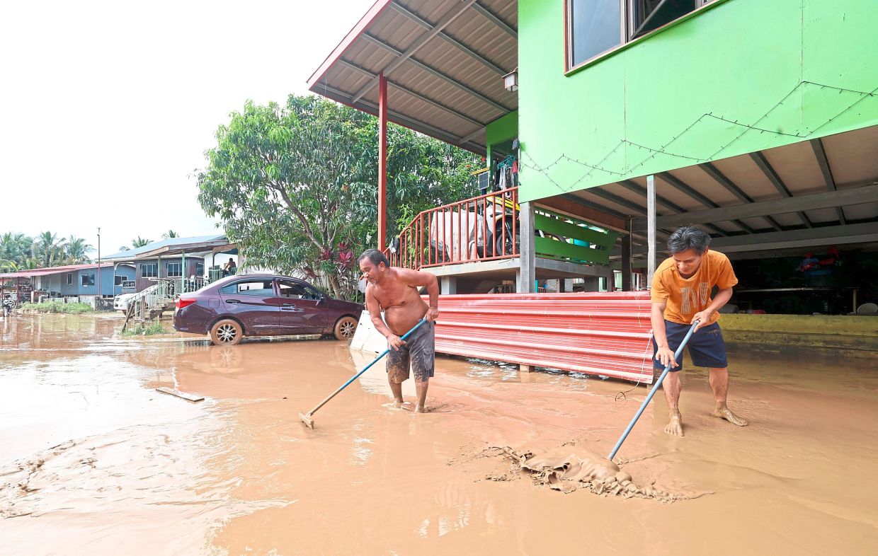 After the deluge: Kampung Rampayan Laut residents clearing mud from their homes following the floods. — Bernama