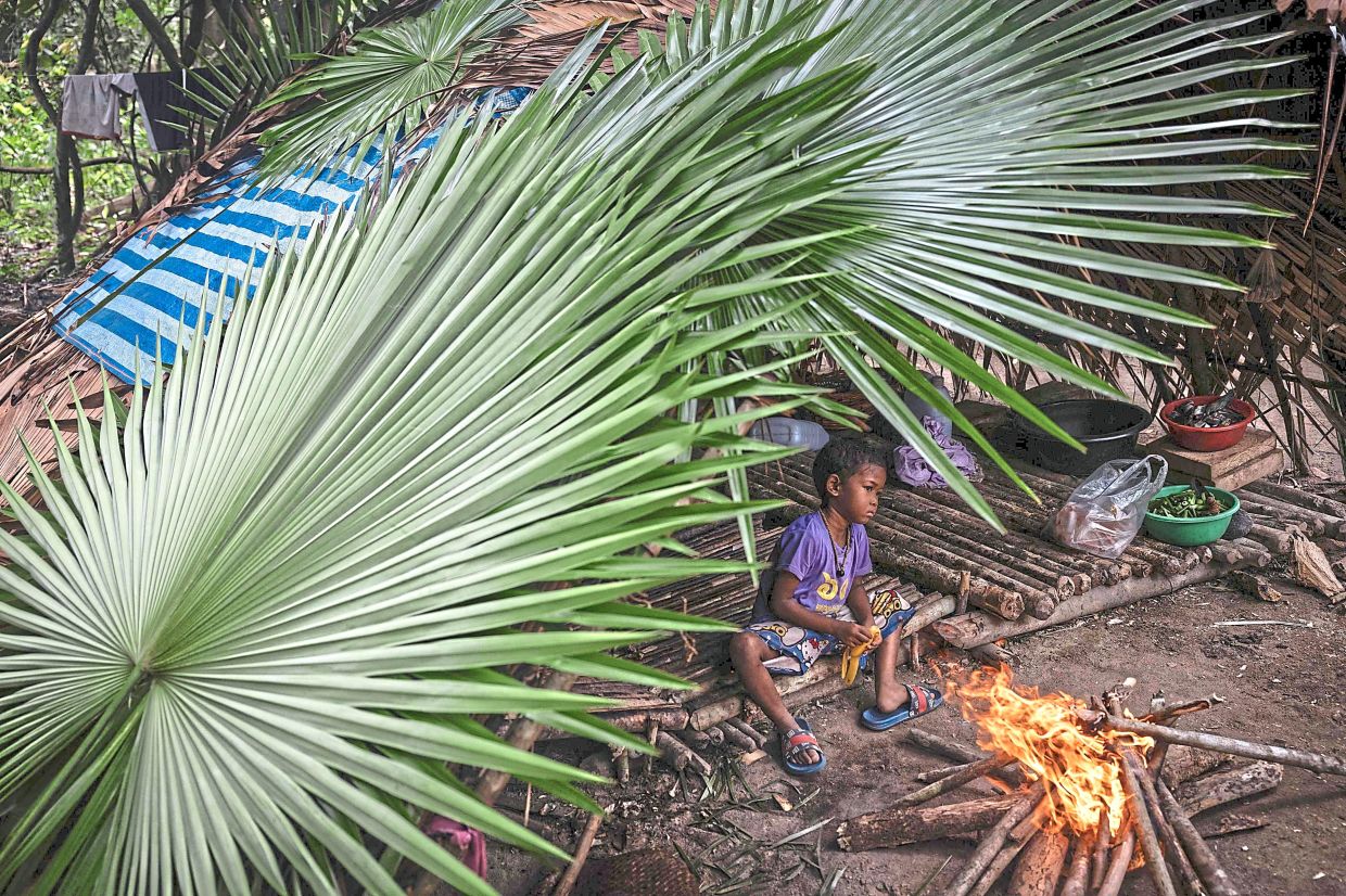 Between worlds: A Maniq child warming himself next to a fire in his hut in Phatthalung in southern Thailand.— AFP
