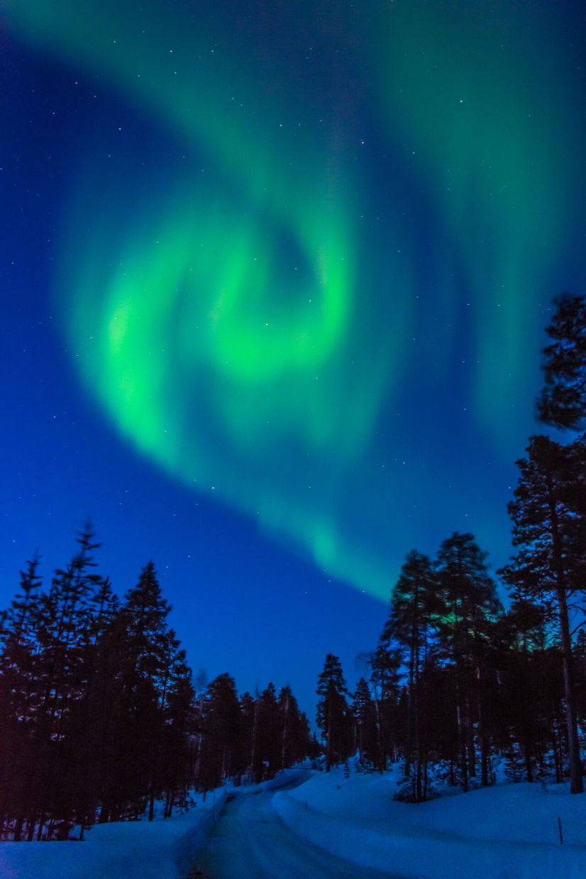 The Northern Lights dancing over a snow-covered Arctic landscape in Finland.
