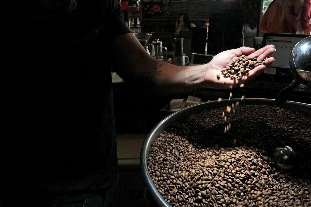 A barista checks freshly roasted coffee beans in a coffee shop in Sao Paulo, Brazil. Even with all the cost pressures, human nature is likely to keep coffee shops alive.
