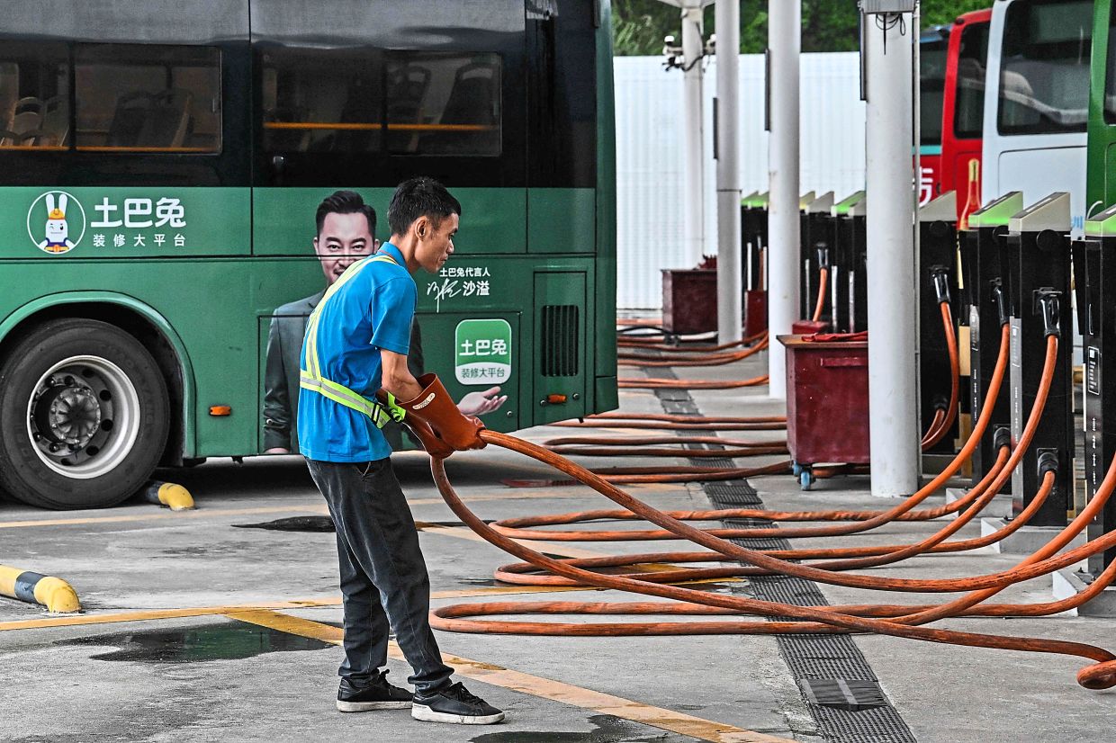 A worker is seen handling charging cables at a charging station in Shenzhen, China, in this photo dated October 2023. This is part of the city’s efforts to improve its public transport network. — AFP