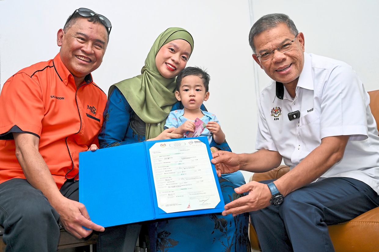 Proper paperwork: Saifuddin Nasution (right) presenting Ahmad Yusuf’s (second from right) identification documents to Nur Hakikah (centre). — RAJA FAISAL HISHAN/The Star