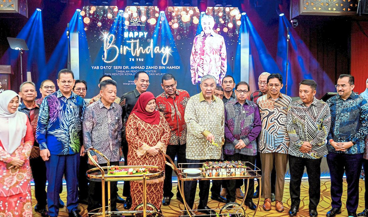 Birthday wishes: Ahmad Zahid cutting his birthday cake after delivering a New Year address at the Rural and Regional Development Ministry yesterday. — Bernama