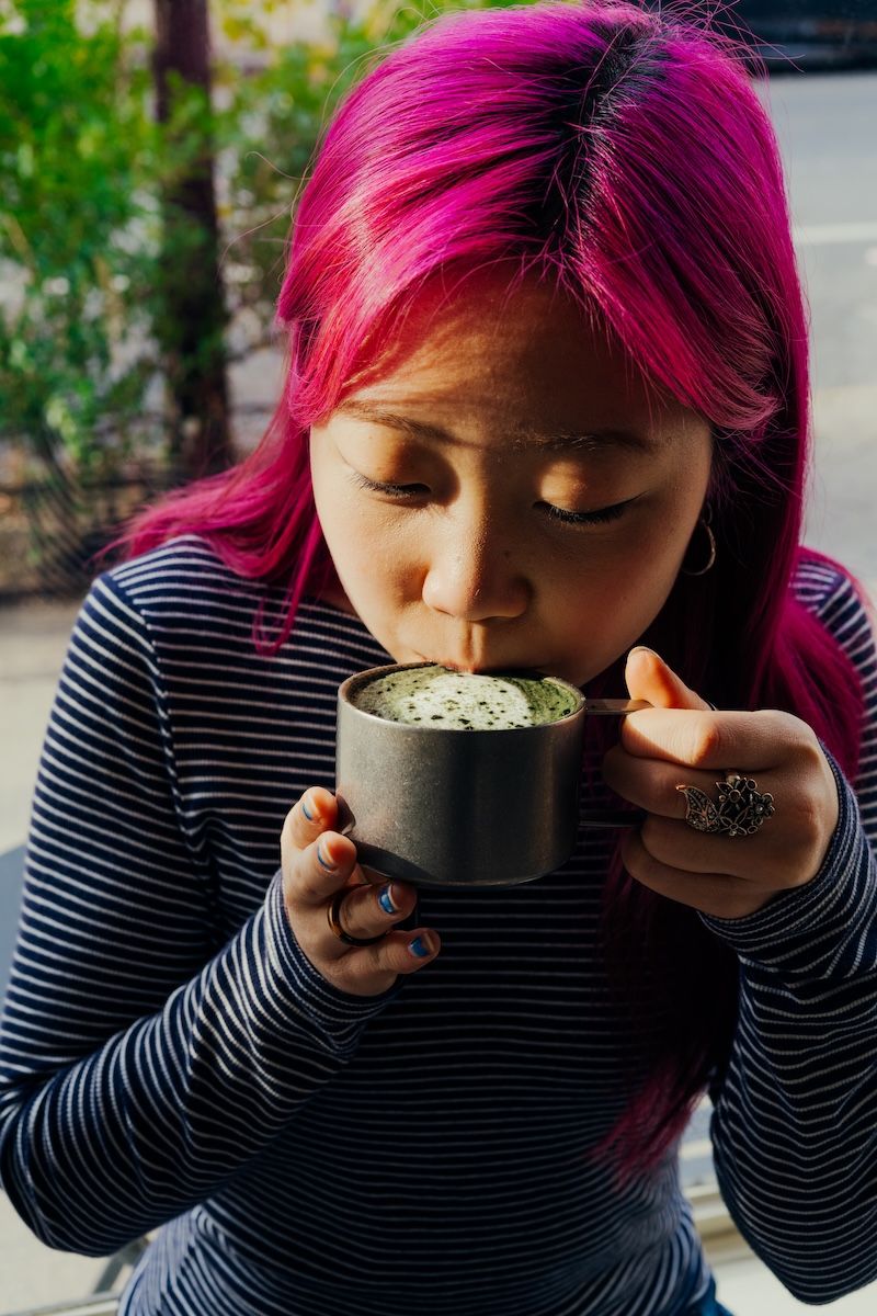 Kayla An drinks a mugwort latte at Dae in New York, Nov. 21, 2025. Caffeine-free drinks, like mugwort lattes, have long been popular in other parts of the world — but they’re gaining traction in the US as more Asian and Middle Eastern cafes open across the country. – Photo: Janice Chung/The New York Times