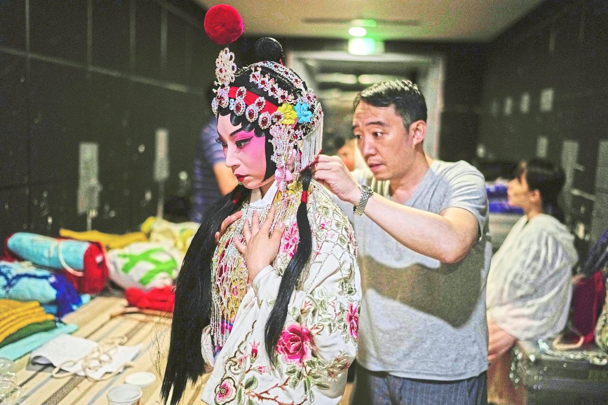 Backstage, Zhang receives assistance putting on her costume before the show. Photo: AP 