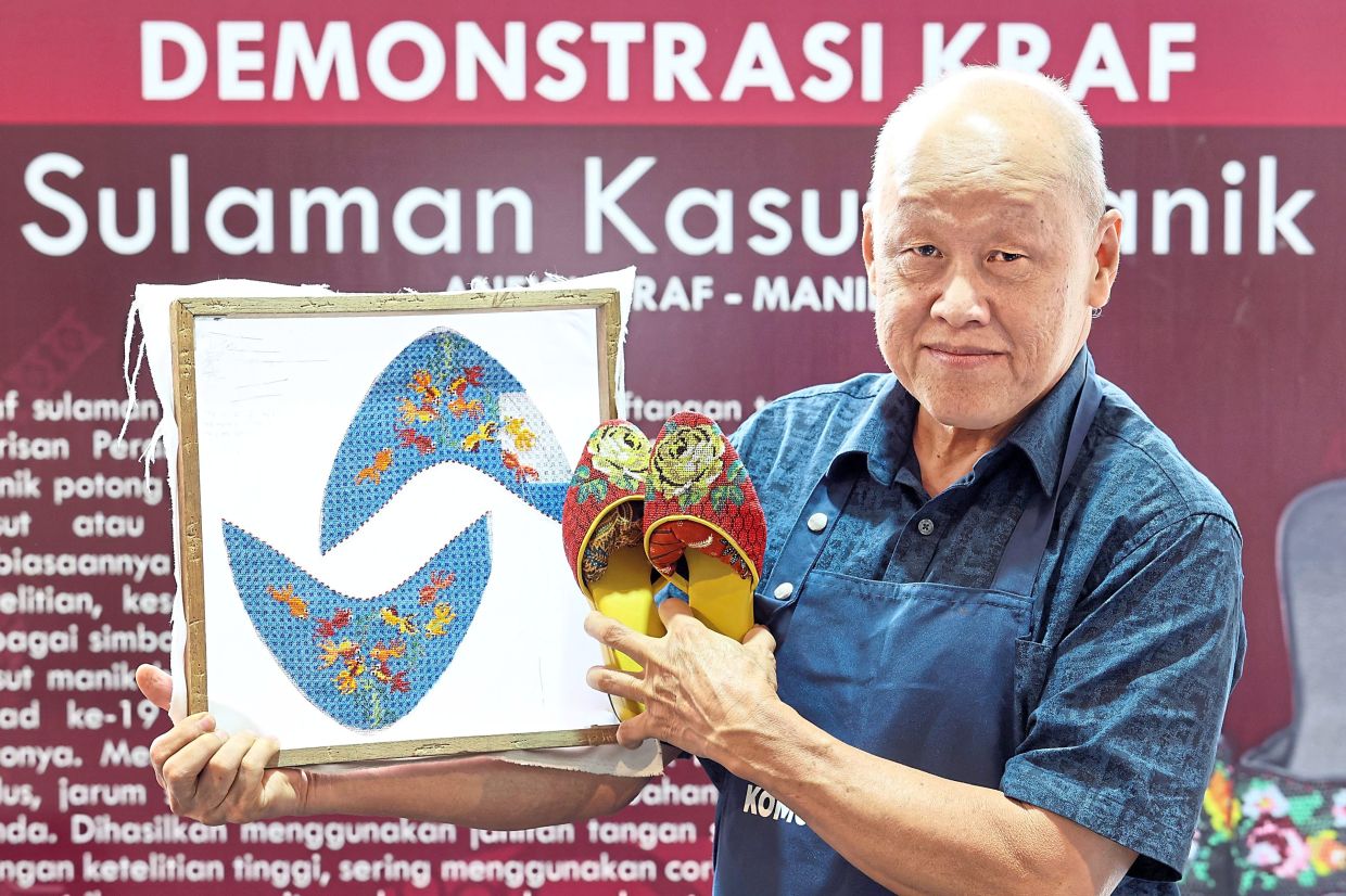 Lim holding a wooden embroidery frame and a pair of beaded shoes.