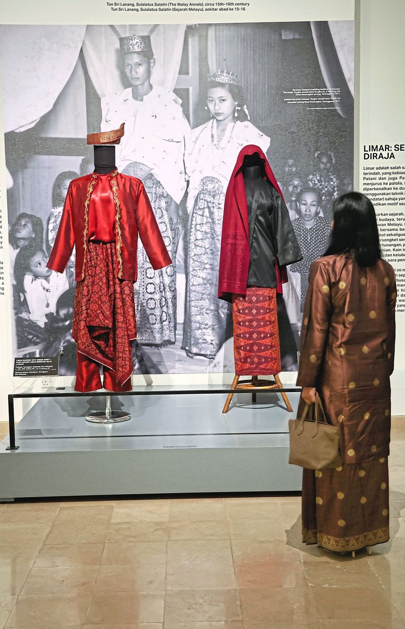 A visitor admires a traditional limar exhibit, a rare weft-ikat textile whose blurred patterns reflect Malay royal prestige and refined courtlyaesthetics.