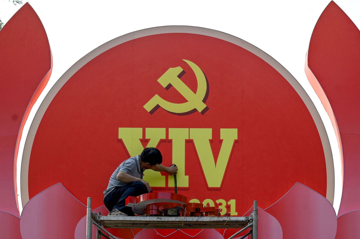 A worker installs a billboard advertising the 14th Congress of the Vietnamese Communist Party in Hanoi on Friday, January 9, 2026. -- Photo by Nhac NGUYEN / AFP