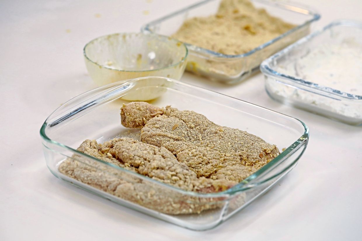 Dredge the marinated chicken in flour, then drench in egg and finally coat with breadcrumbs before frying over medium low heat until golden and crispy.