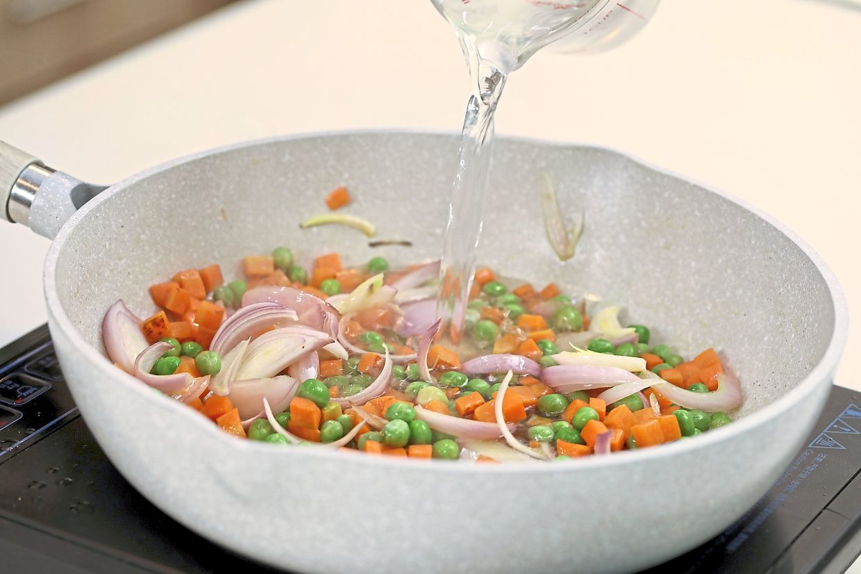 Saute carrots, onions and green peas until cooked, then add the sauce ingredients of water, tomato ketchup, chilli sauce, soy sauce, Worcestershire sauce, chicken bouillon, salt and sugar to taste, and finally tomato wedges and cornflour to thicken.