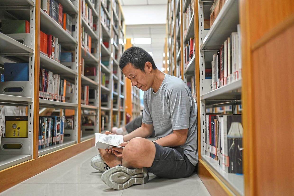 Quiet moment: Hu reading a book at a public library in Chengdu. His new literary career offers some much-needed financial security. — AFP