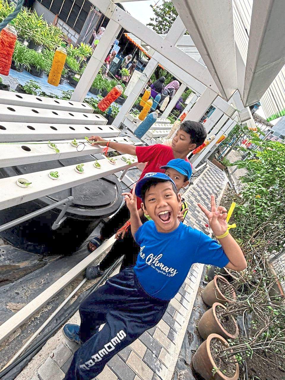 Schoolchildren learn about hydroponics, composting and fish feeding while on an educational tour of the Flat Sri Serdang community garden. — Courtesy photo