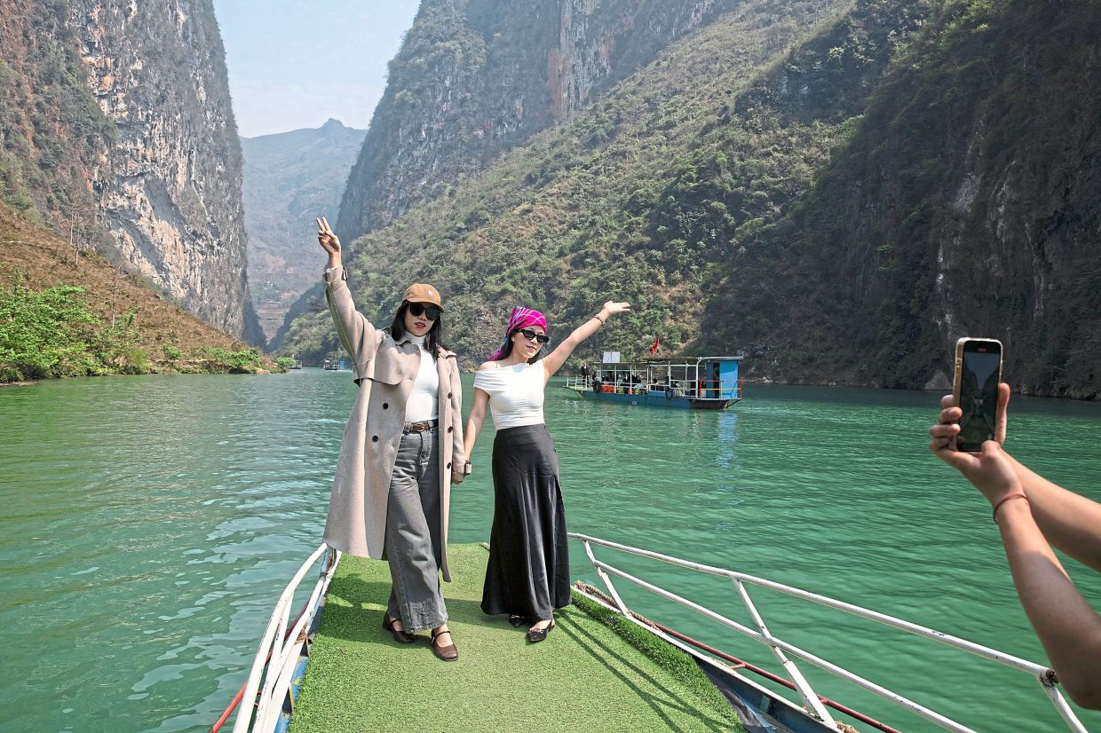 Travellers posing for photos between towering walls of the Tu San Canyon.