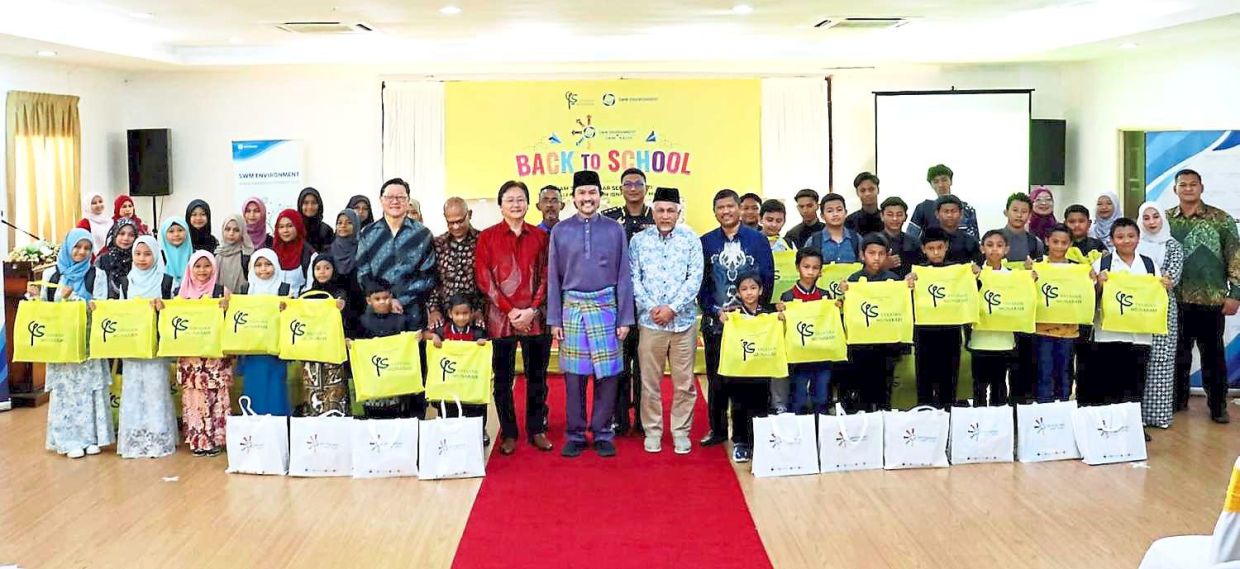 Yayasan Munarah chairman Tunku Ali (centre) posing with guests and children after a presentation ceremony at a resort in Seri Menanti, where he distributed back-to-school supplies to underprivileged students early last year under the Yayasan Munarah X SWM Kasih Back to School initiative.