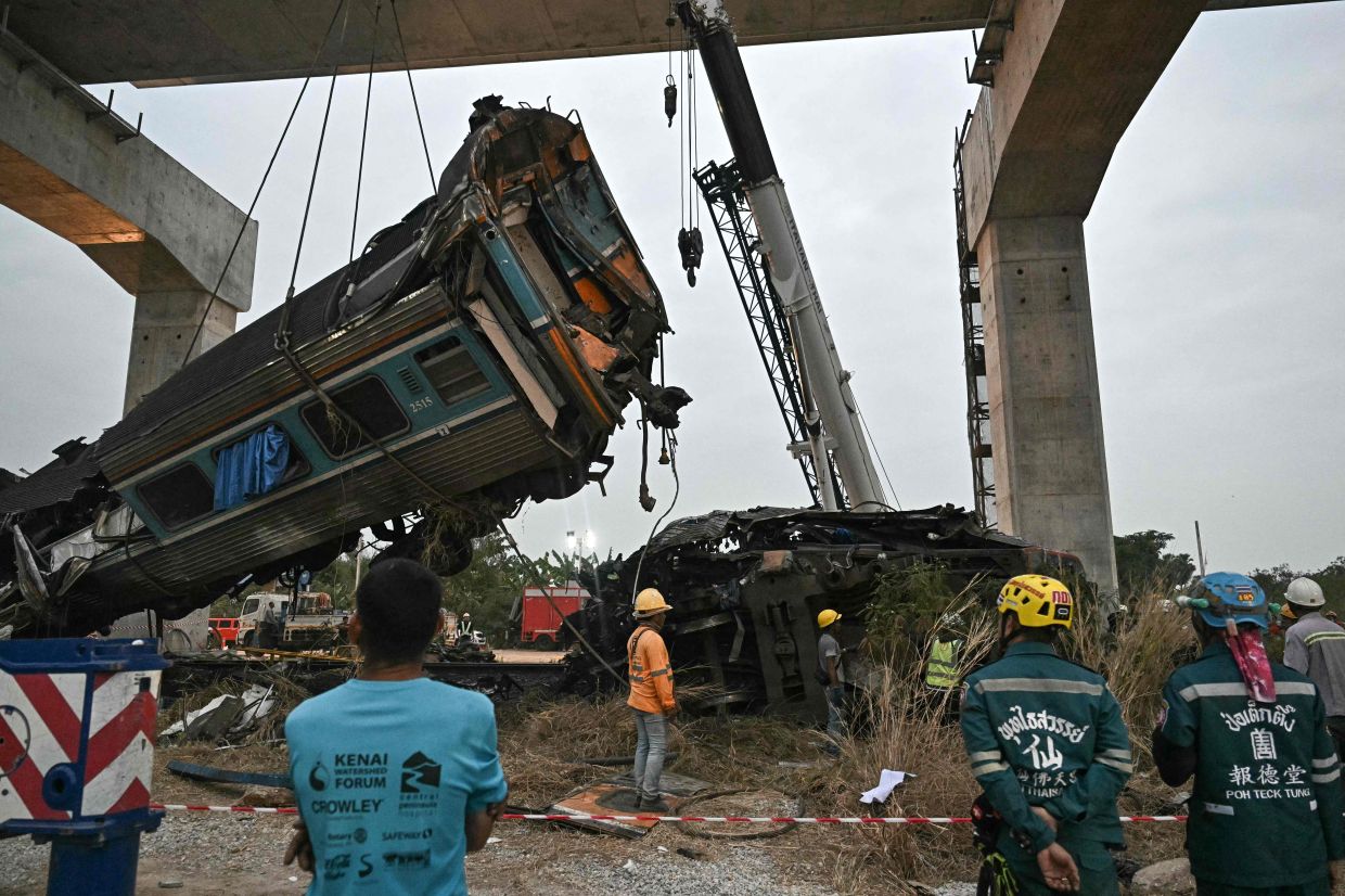 Recovery workers watch as a carriage of a train that crashed when a construction crane collapsed is lifted off the tracks in Thailand's Nakhon Ratchasima province on January 14, 2026. A crane at a China-backed high-speed rail project in Thailand collapsed onto a passenger train on January 14 and caused it to derail, killing at least 28 people and injuring dozens more, authorities said. - Photo: AFP