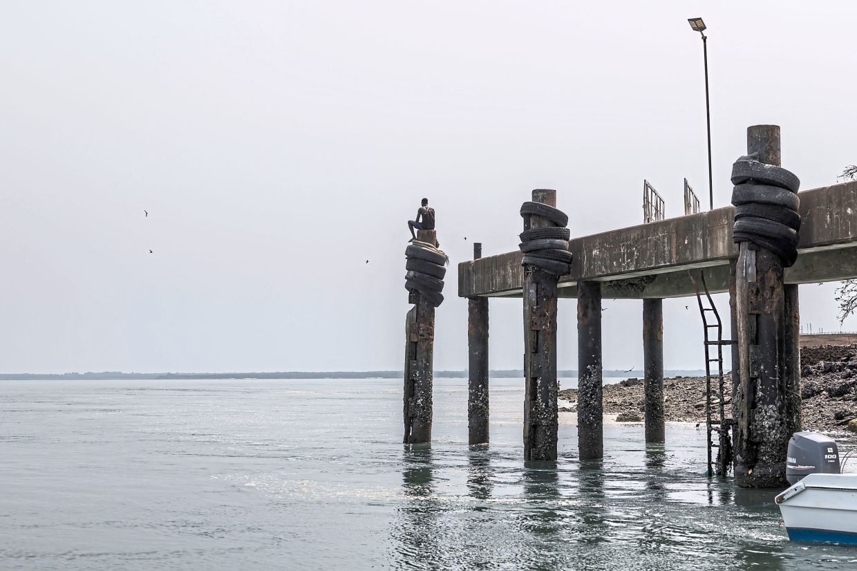 A man sitting by the pier on the island of Bubaque in the Bijagos Archipelago. — AFP