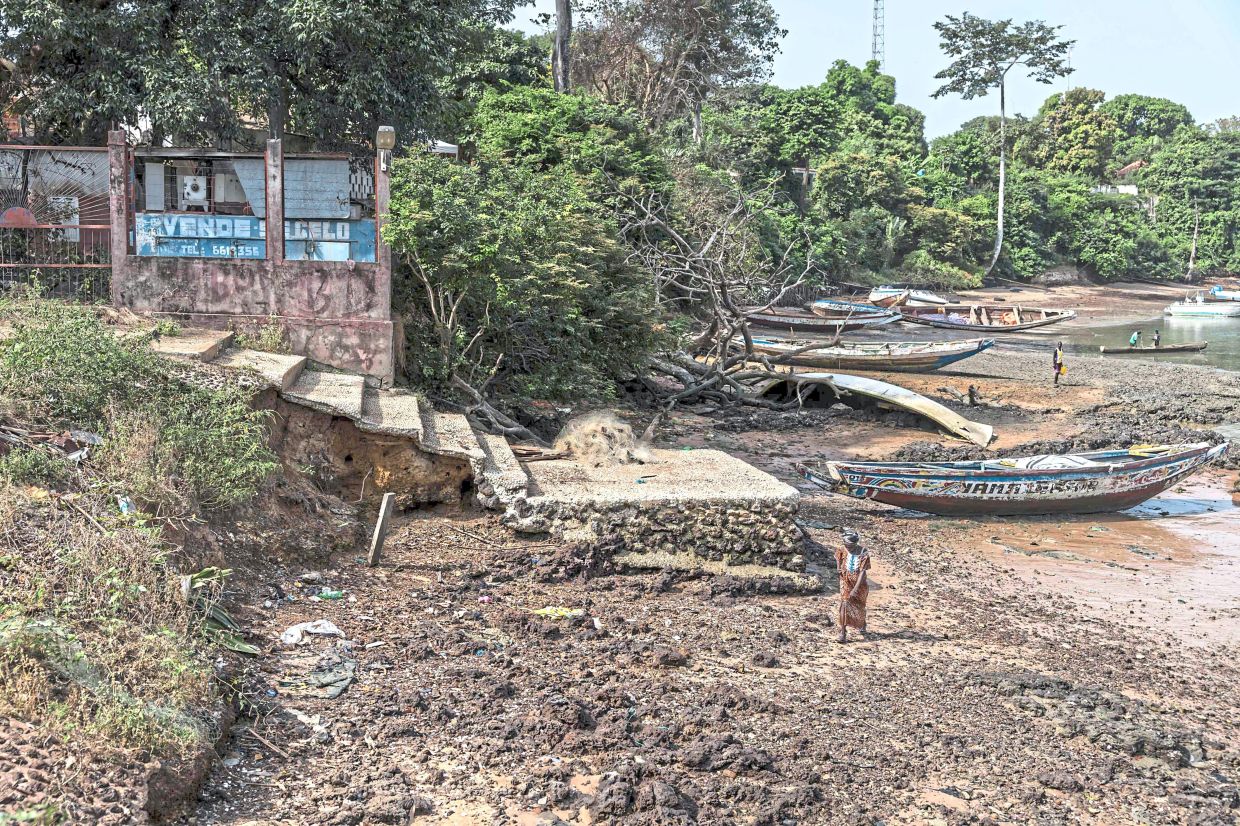 A resident walking past a section damaged by the effects of coastal erosion on the island of Bubaque in the Bijagos Archipelago. — AFP