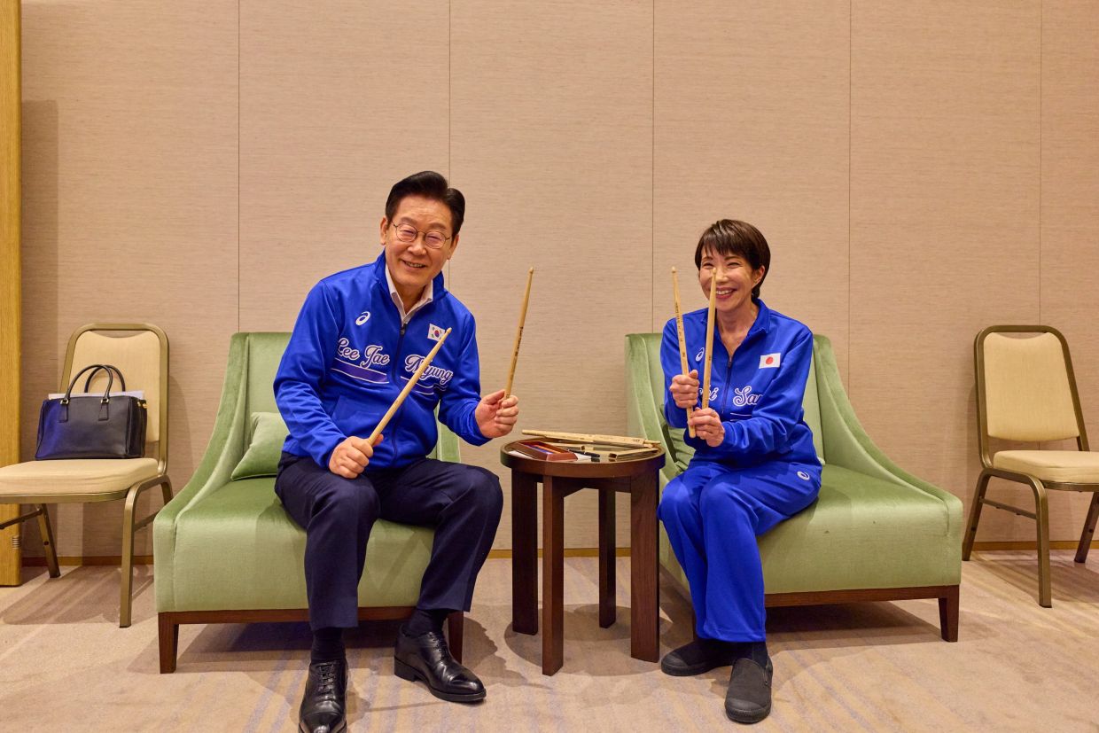 Japanese Prime Minister Sanae Takaichi and South Korean President Lee Jae Myung pose with autographed drumsticks. Photo: Reuters