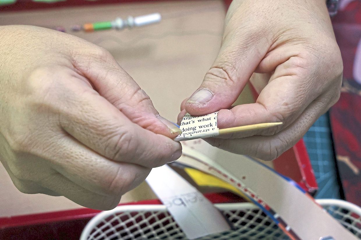 A paper strip in the process of being rolled into a bead.