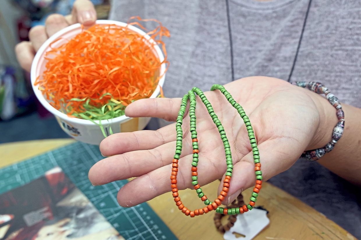 Examples of paper strips rolled into beads for a necklace.