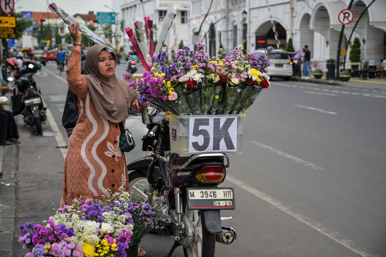 A woman arranges bouquets on her motorcycle to sell in Surabaya on Saturday, January 17, 2026. (Photo by JUNI KRISWANTO / AFP)