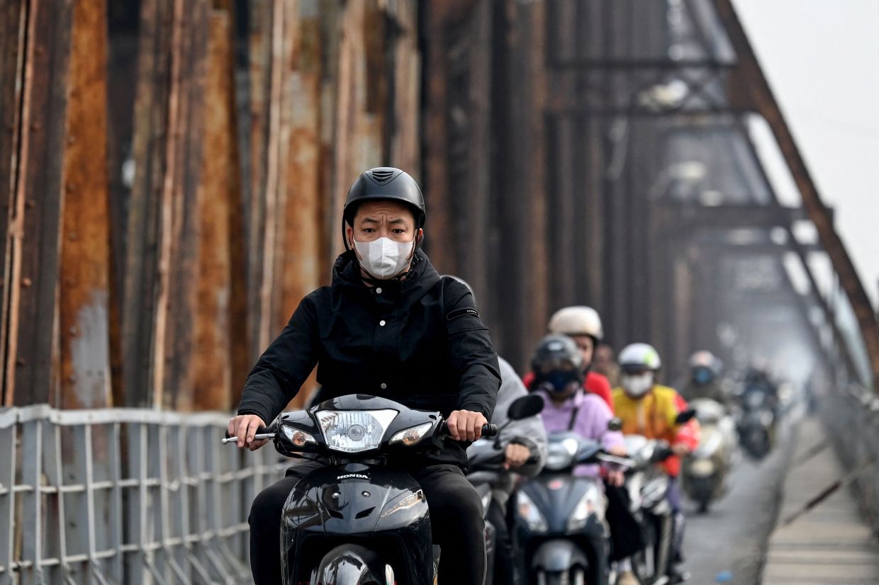 Motorists wearing face masks cross Long Bien bridge on a polluted day in Hanoi. -- Photo by Nhac NGUYEN / AFP