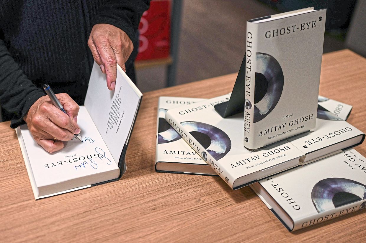 Ghosh signing a copy of his novel ‘Ghost-Eye’ during its promotional tour in New Delhi. Photo: AFP 