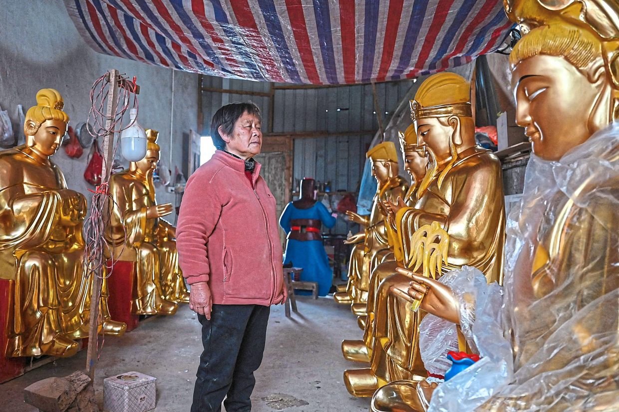 Gu checking on Buddhist sculptures after the gilding process at a workshop at the village in Suzhou, Jiangsu province. — AFP
