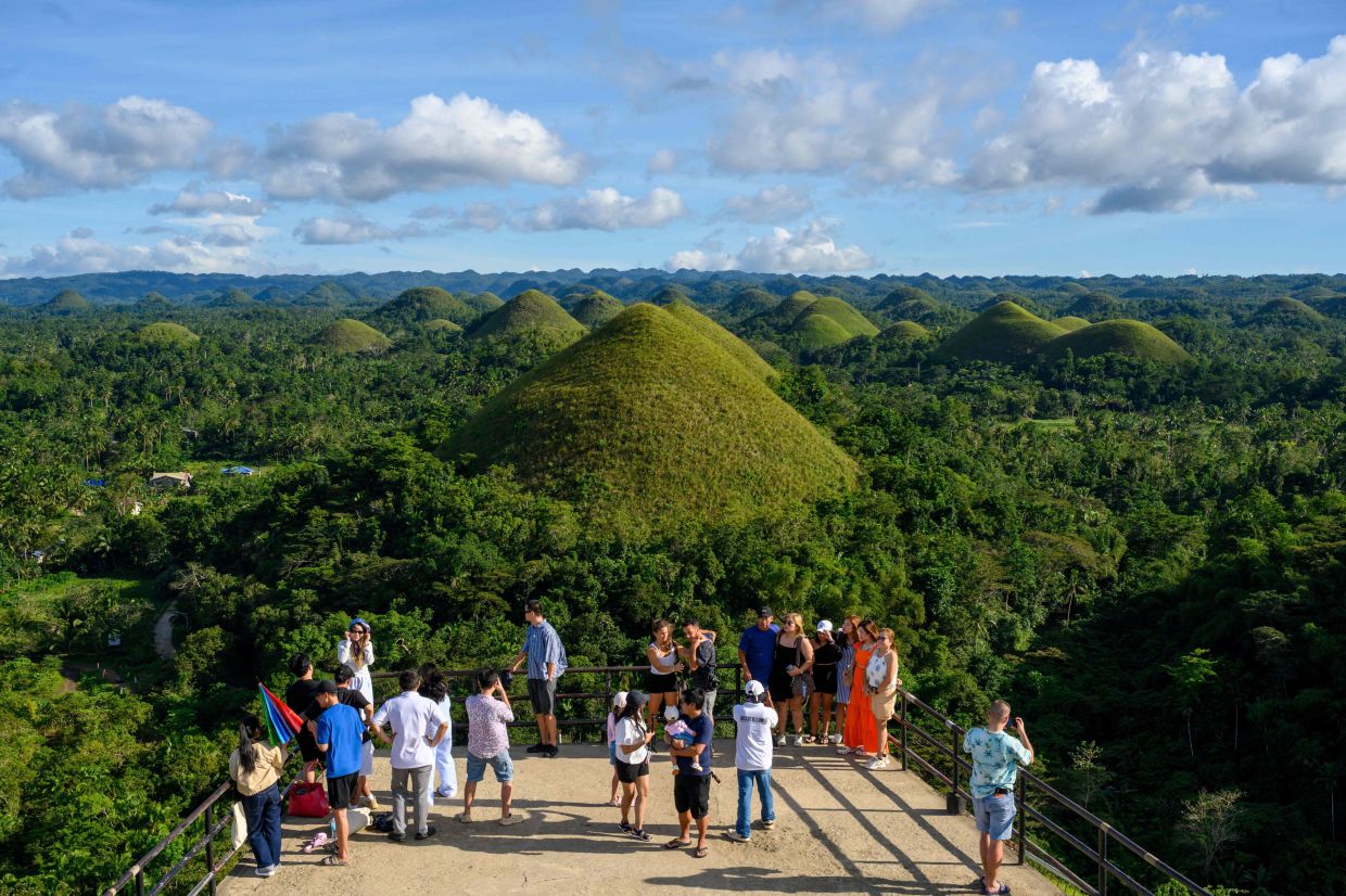 Tourists looking at the iconic Chocolate Hills on Bohol Island in Central Visayas province in the Philippines. Global tourism hit a new record level in 2025, according to UN Tourism, AFP reports on Tuesday, January 20, 2026. -- Photo by Mladen ANTONOV / AFP