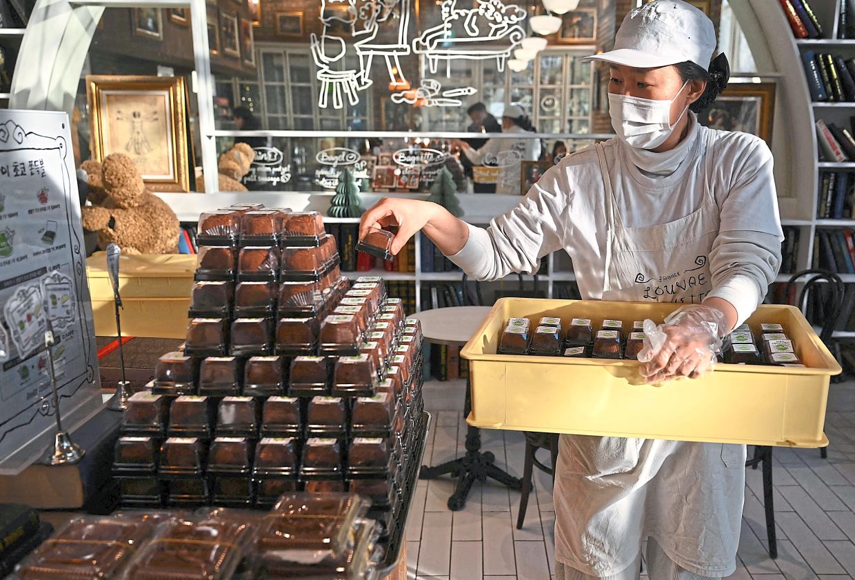 Delicious draw: An employee placing ‘Dubai-style’ chewy chocolate cookies on a display table at a bakery cafe in Seoul. — AFP