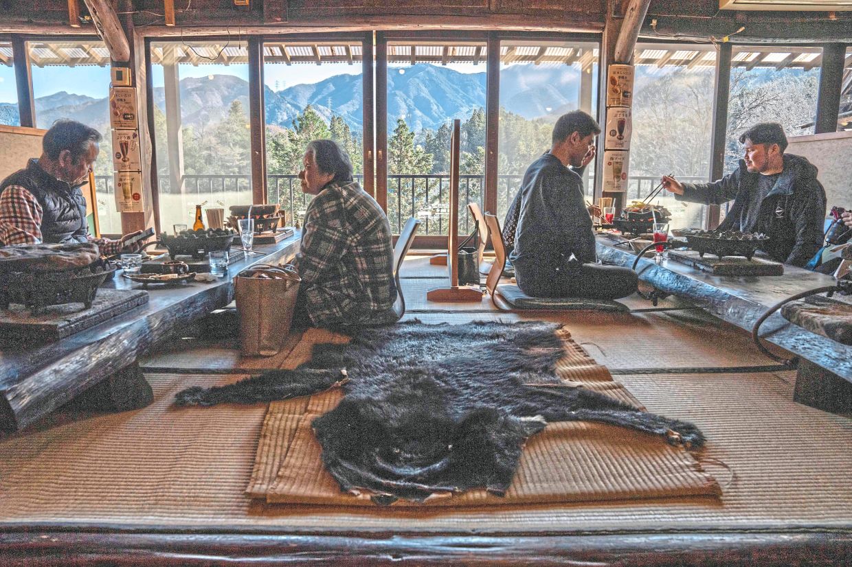 People eating next to a bear skin rug at a restaurant which offers bear meat in Chichibu, Saitama prefecture, in this photo taken on Dec 12, 2025.— AFP