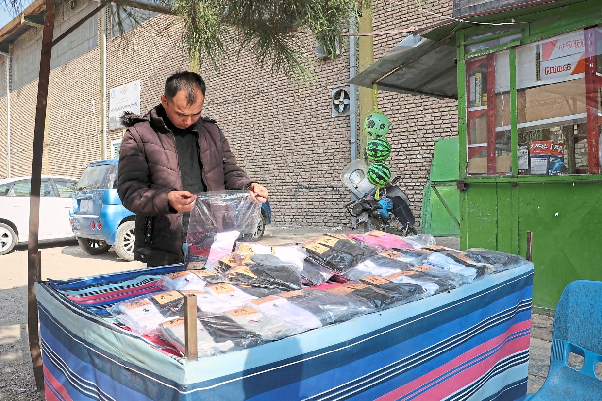 Mohammad Arif Jafari prepares his stall to sell socks made in the workshop.