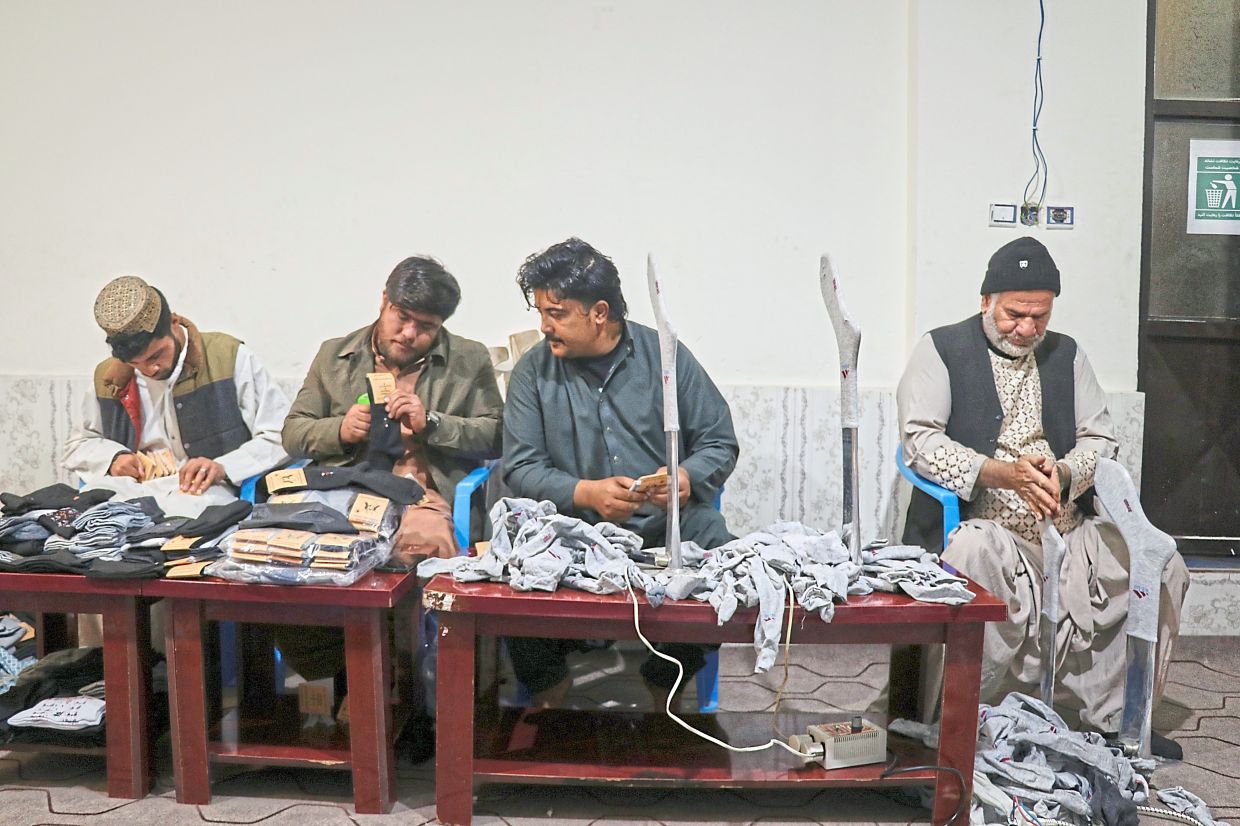 Amiri (second from left) labels a pair of socks as he works with his staff, all of whom have disabilities. 
