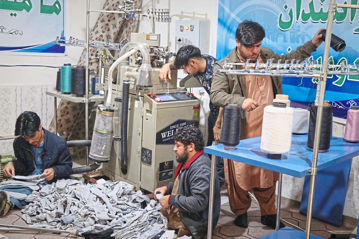Amiri (right) sorts out spools of thread for making socks. 