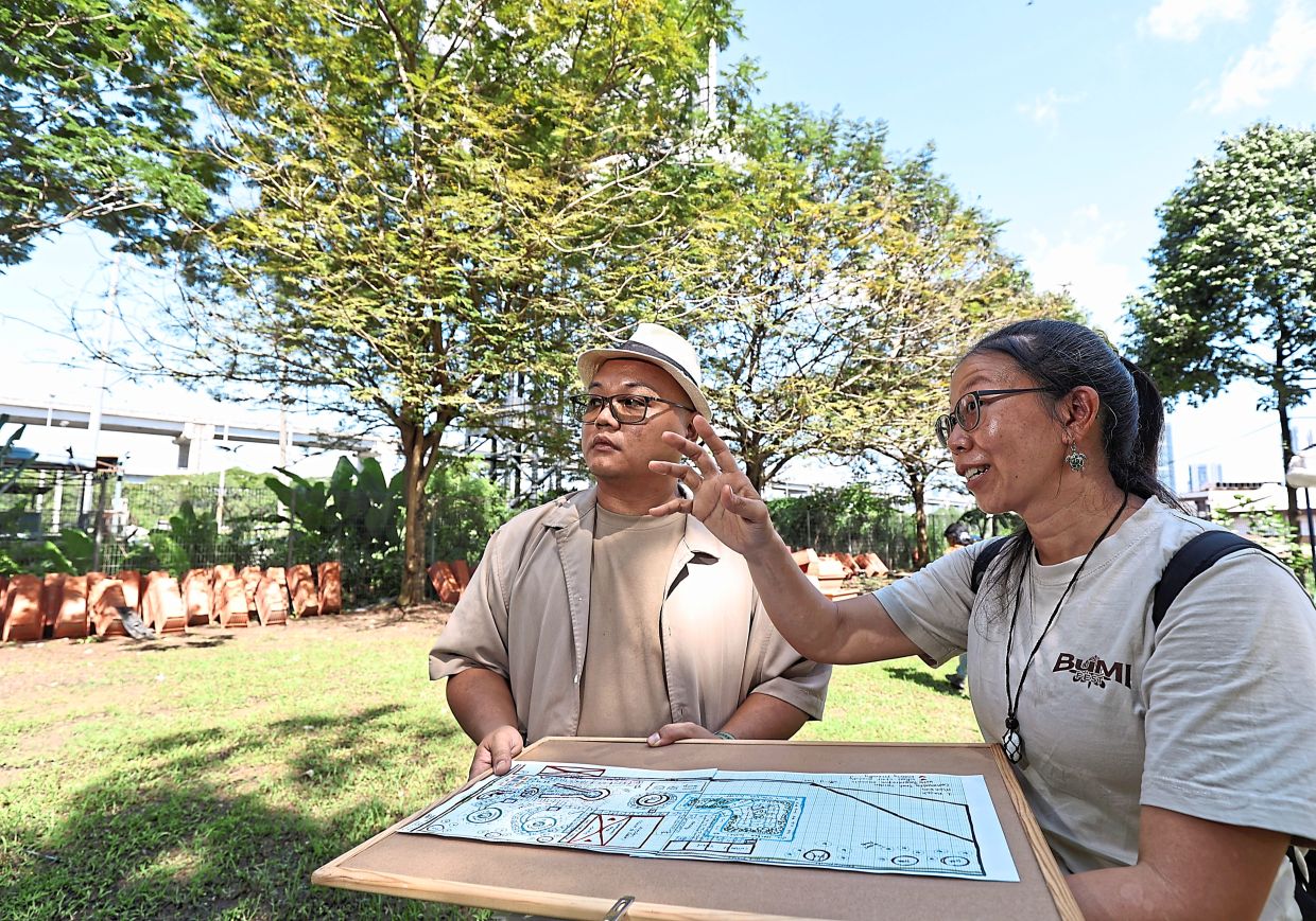 Chua (right) shows 1 Razak Mansion management corporation chairman Anthony Tan her sketched plan. Photo: The Star/Azman Ghani