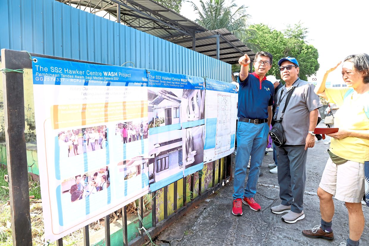 Rotarians discussing the SS2 Hawker Centre WASH project in front of plans put up at the site. — Photos: ART CHEN/The Star