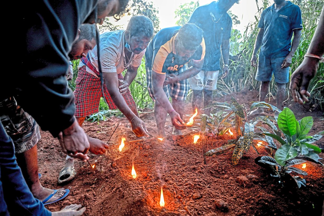 Family members and locals praying at a grave in Kandy District. — Atul Loke/The New York Times