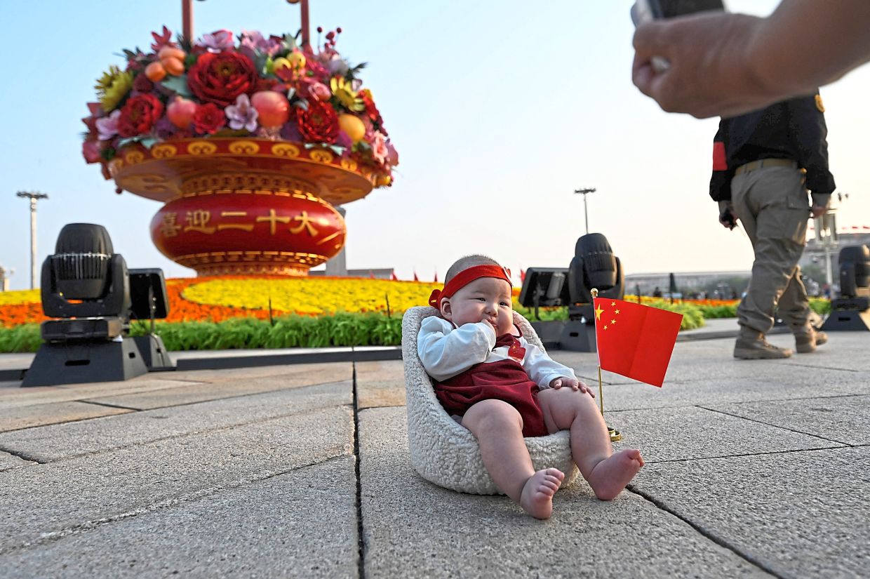 Next generation: A file photo of a woman taking a photo of a baby in front of an installation celebrating the National Day in Beijing on Sept 29, 2022. — AFP/AP