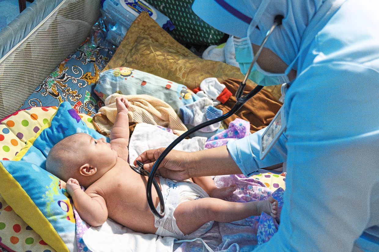 A community nurse and midwife assesses a baby’s health during a post-delivery home visit in Semenyih, Selangor. Nurses are the backbone of the health system, but Malaysia currently faces a shortage of over 20,000 nurses. — World Health Organization