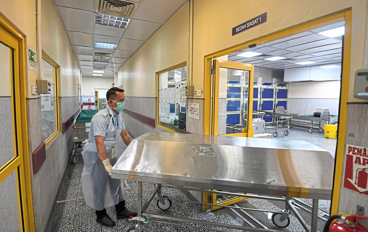 UMMC medical assistant Hasrul Haziq wheeling a body into the autopsy suite for a post-mortem.
