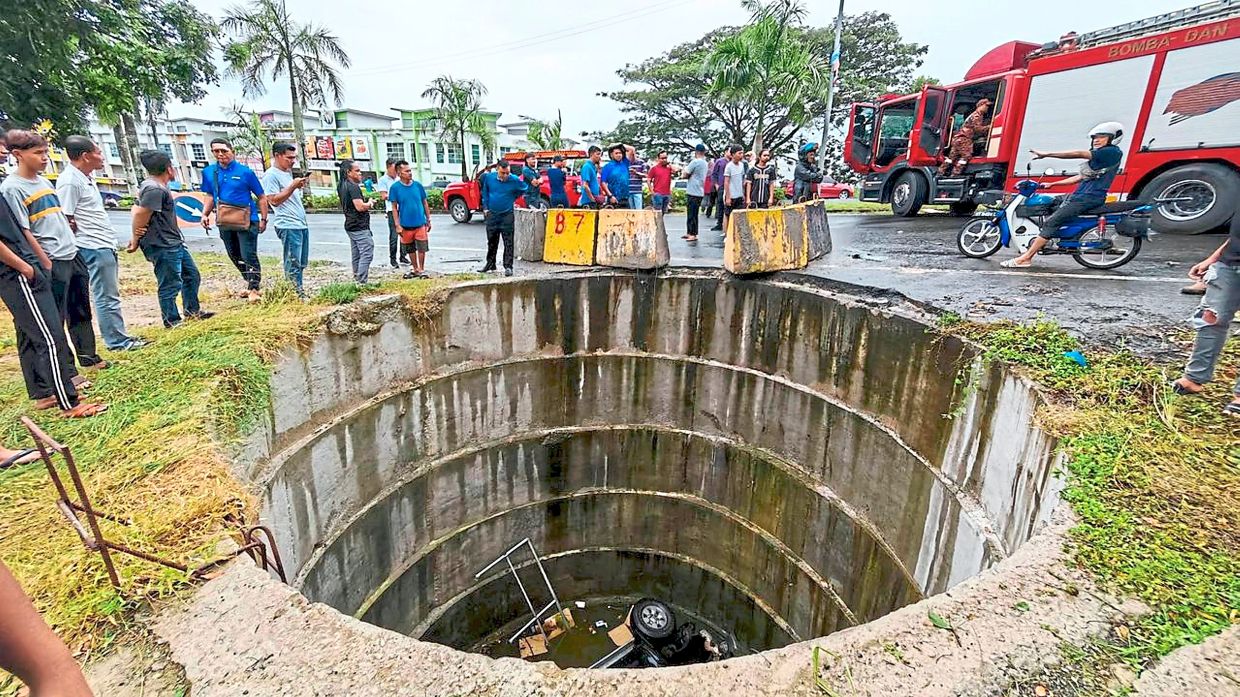 Deep plunge: Onlookers gathering at the accident scene in Lahad Datu as emergency services arrive.