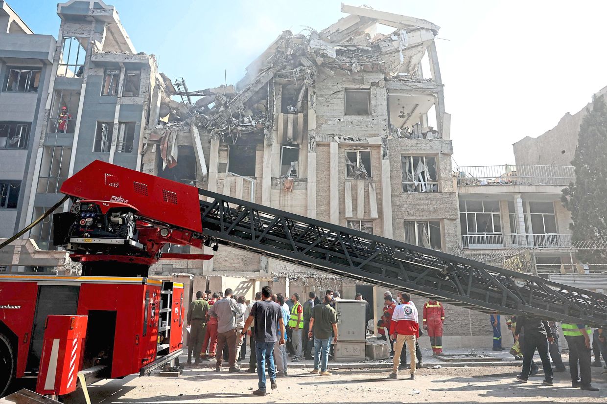 Rescue teams working outside a heavily damaged building targeted by an Israeli strike in Tehran in June last year. —AFP
