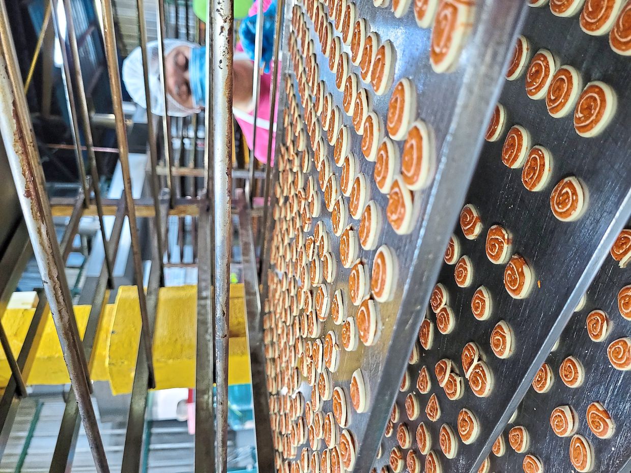 A worker lining up Koza’B Mini Spiced Wheel Cookies to be baked.