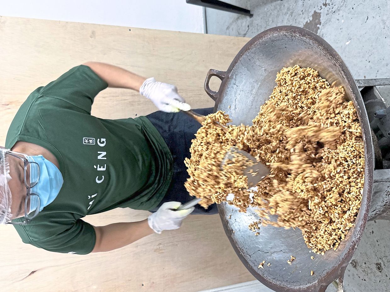 Wong cooking rice crackers in a big wok.