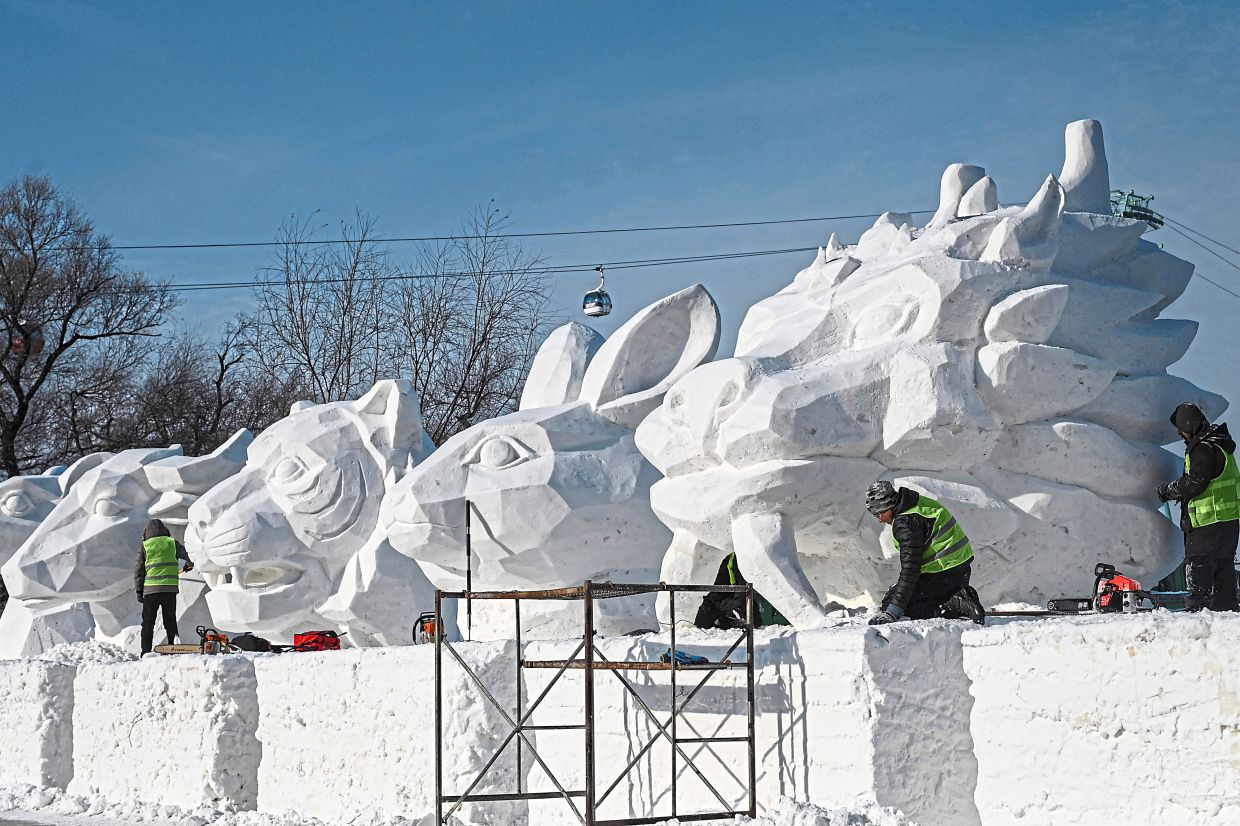 3. Workers carving a large snow sculpture in a public square in Harbin as part of festival preparations. — AFP 