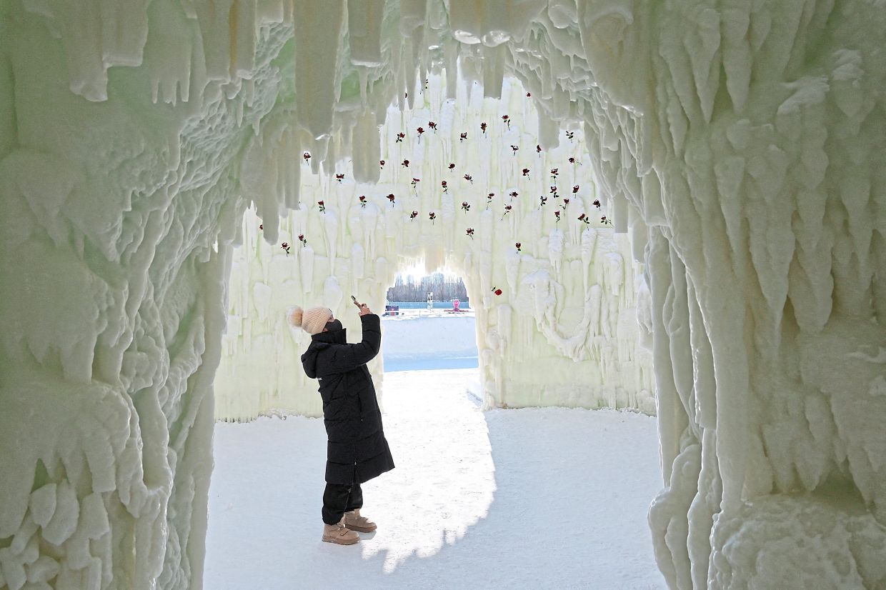 5. A visitor photographing the interior of an elaborate ice structure at the festival. — Reuters