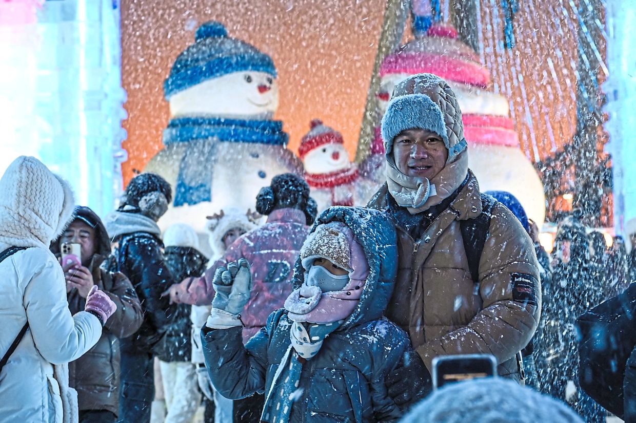 8. Festival-goers taking photos with artificial snow at the opening of the event. — AFP