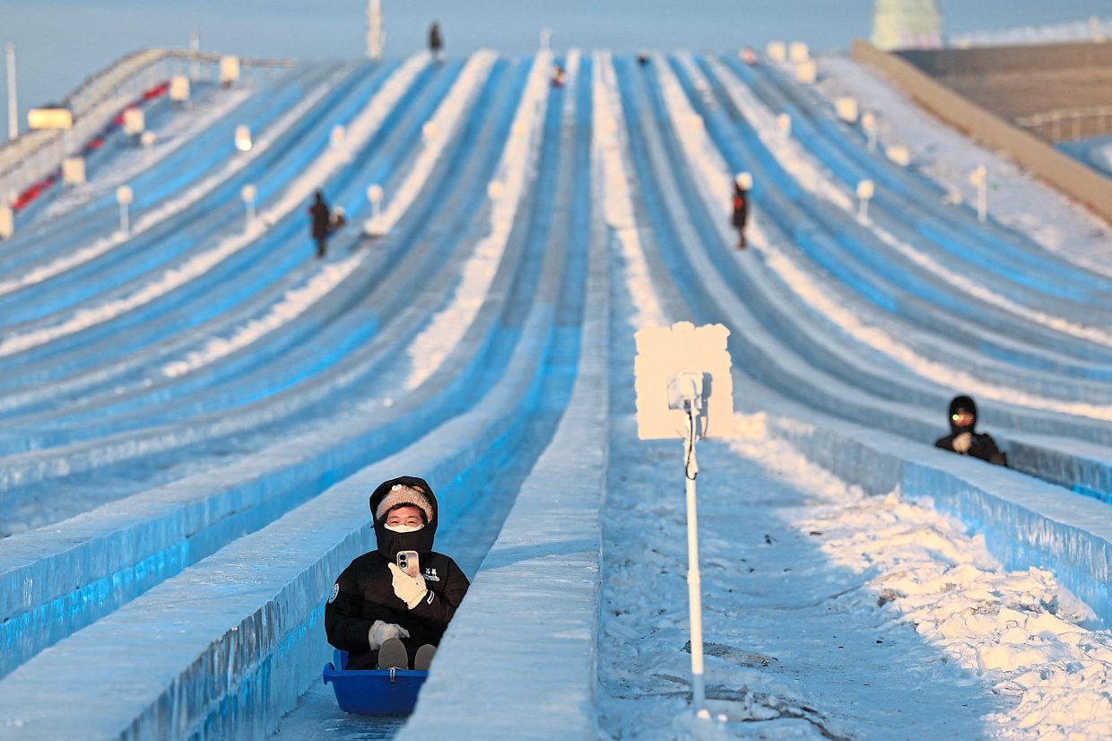 2. A person sliding down a giant ice slide at the annual Ice and Snow Festival in Harbin. — Reuters