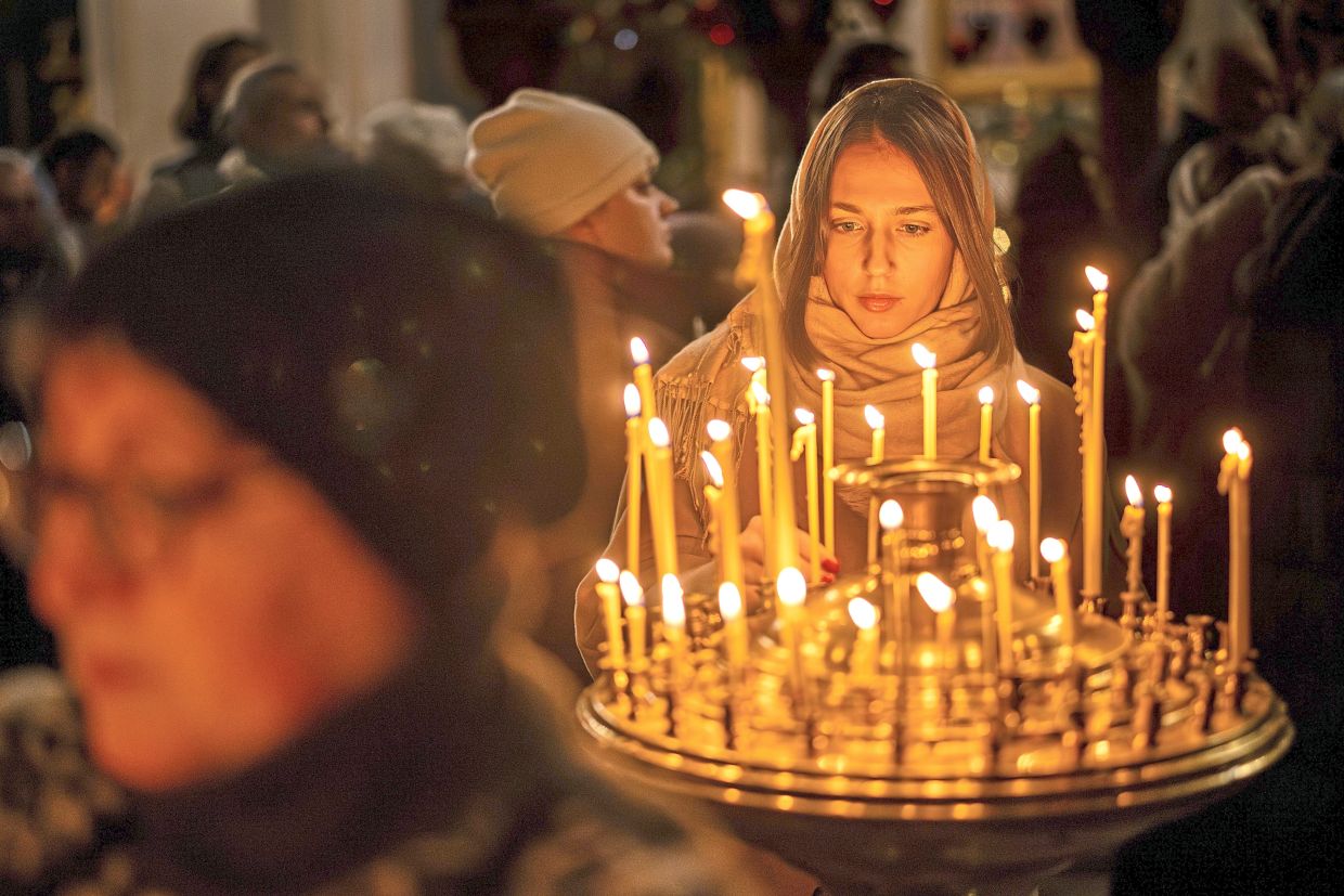 4. A worshipper lighting candles ahead of the liturgy on Orthodox Christmas eve at the Church of the Holyspirit in Vilnius, Lithuania. — AP